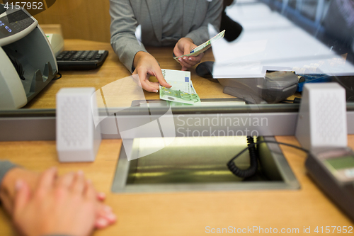 Image of clerk giving cash money to customer at bank office