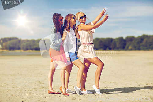 Image of group of smiling women taking selfie on beach