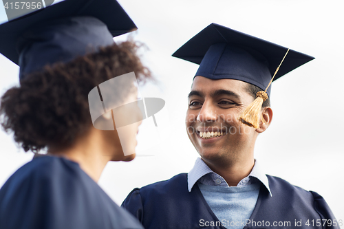 Image of happy students or bachelors in mortar boards