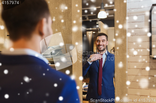 Image of man trying tie on at mirror in clothing store