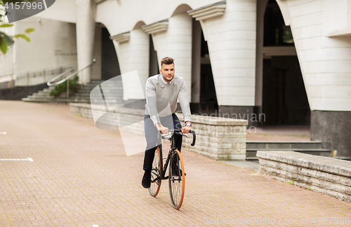 Image of young man riding bicycle on city street