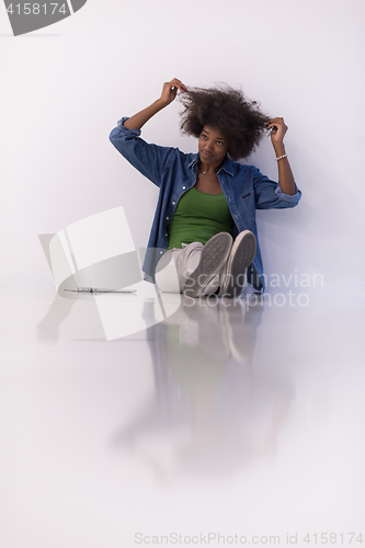 Image of african american woman sitting on floor with laptop