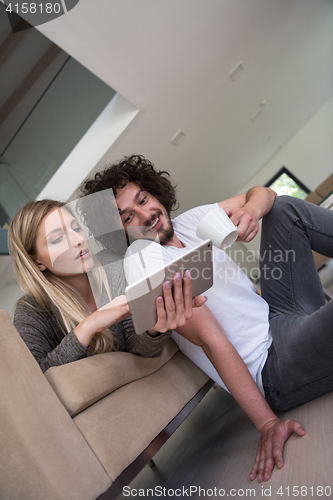 Image of couple relaxing at  home with tablet computers