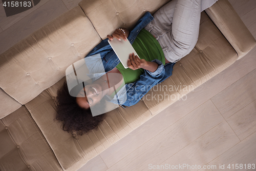 Image of african american woman at home with digital tablet top view