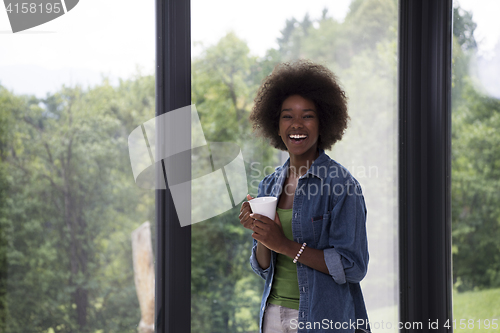 Image of African American woman drinking coffee looking out the window