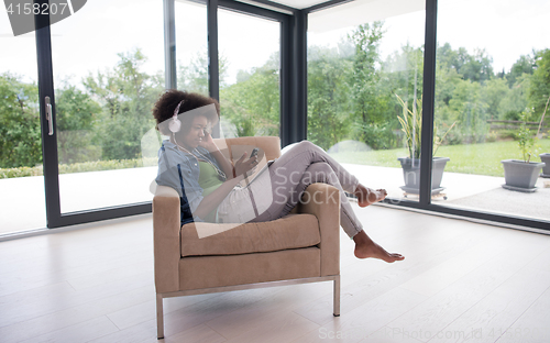 Image of African american woman at home in chair with tablet and head pho