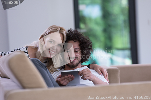 Image of couple relaxing at  home with tablet computers