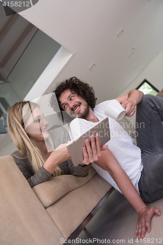 Image of couple relaxing at  home with tablet computers