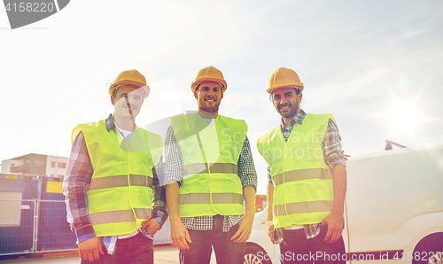 Image of happy male builders in high visible vests outdoors