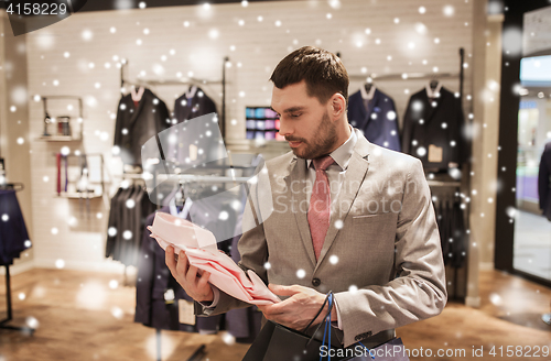 Image of man with bags choosing shirt in clothing store