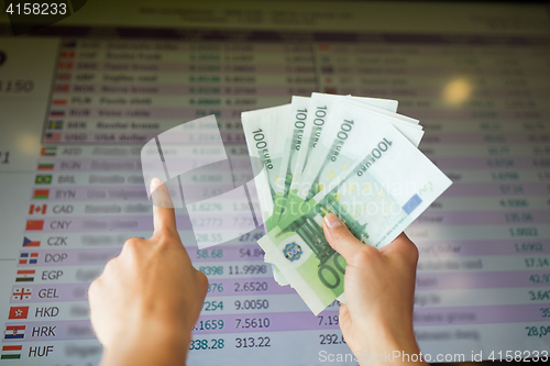 Image of hands with euro money over currency exchange rates