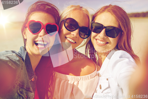 Image of group of smiling women taking selfie on beach