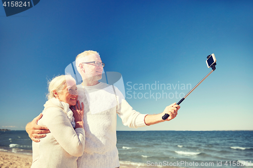 Image of seniors with smartphone taking selfie on beach