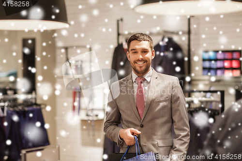 Image of happy man with shopping bags at clothing store