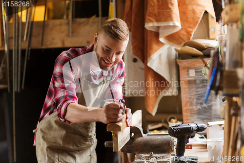 Image of carpenter working with plane and wood at workshop