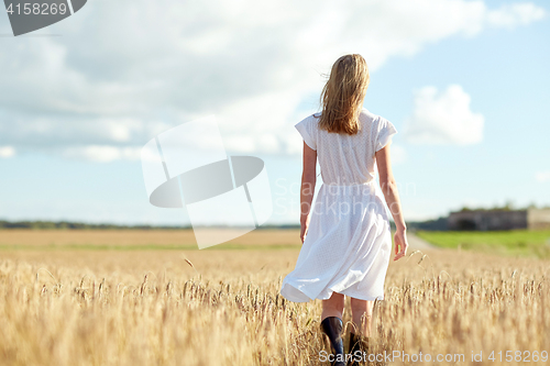 Image of young woman in white dress walking along on field
