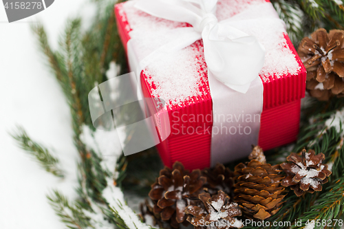 Image of close up of christmas gift and fir wreath on snow