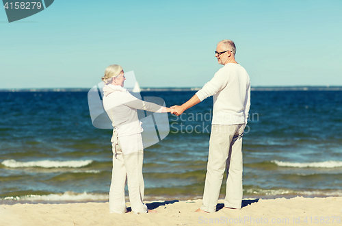 Image of happy senior couple holding hands on summer beach