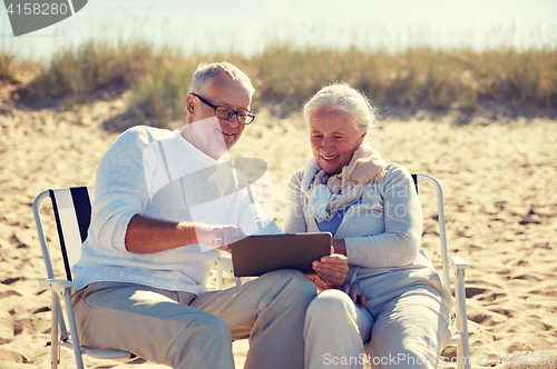 Image of happy senior couple with tablet pc on summer beach