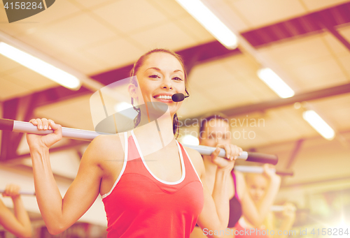 Image of group of smiling people working out with barbells