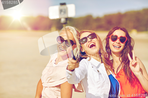 Image of group of smiling women taking selfie on beach