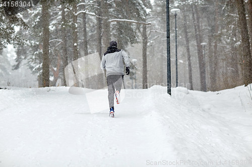 Image of man running on snow covered winter road in forest