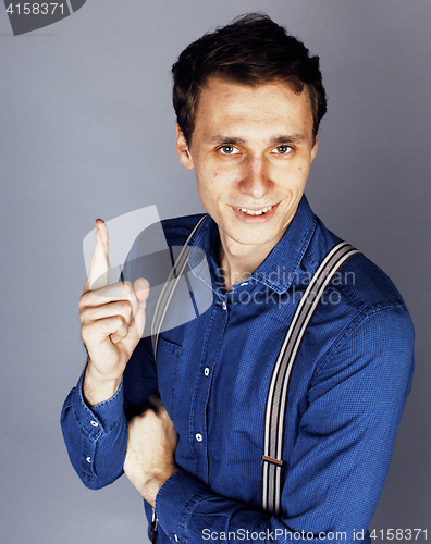 Image of young goofy man with pimples pointing in studio