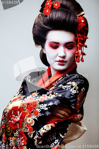 Image of young pretty geisha in black kimono among sakura, asian ethno