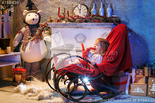 Image of Little girl and rocking chair near fireplace