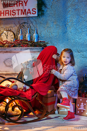 Image of Little girl and rocking chair near fireplace