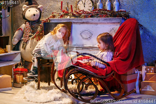 Image of Little girls and rocking chair near fireplace