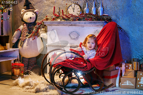 Image of Little girl and rocking chair near fireplace