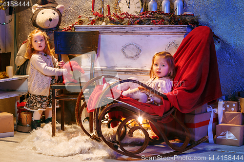 Image of Little girls and rocking chair near fireplace