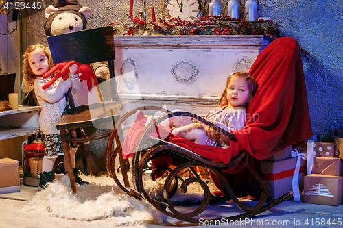 Image of Little girls and rocking chair near fireplace