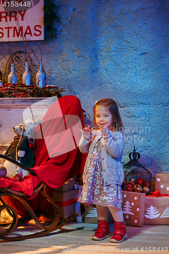 Image of Little girl and rocking chair near fireplace