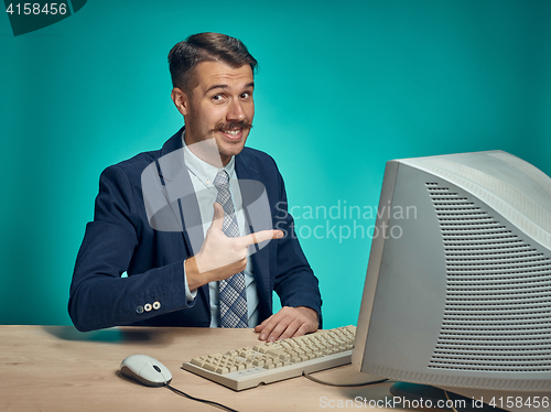 Image of Portrait of cheerful young businessman sitting with computer