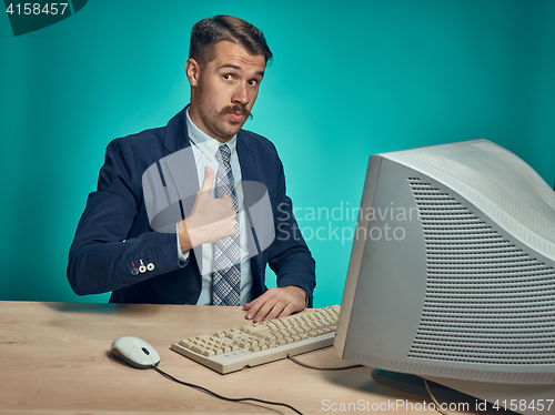 Image of Portrait of cheerful young businessman sitting with computer