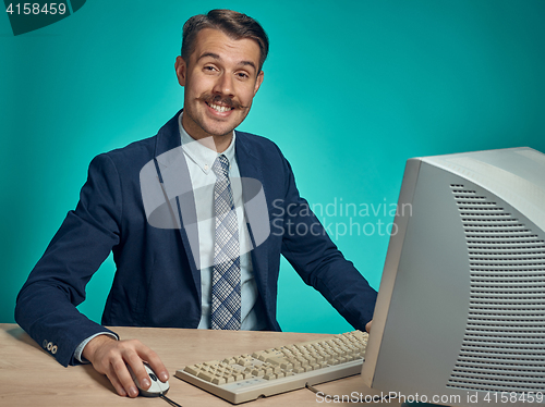 Image of Portrait of cheerful young businessman sitting with computer