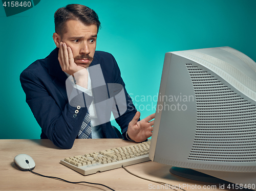 Image of Sad Young Man Working On computer At Desk