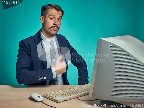 Image of Portrait of cheerful young businessman sitting with computer