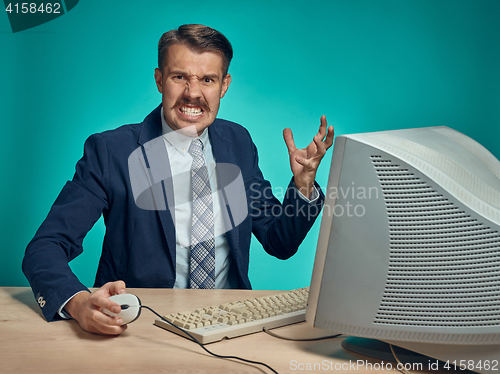 Image of Angry businessman using a monitor against blue background