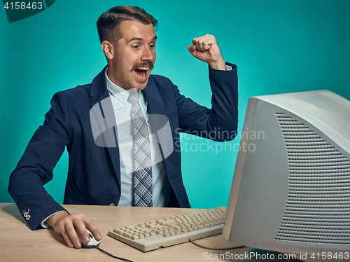 Image of Portrait of cheerful young businessman sitting with computer