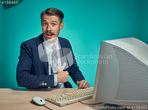 Image of Portrait of cheerful young businessman sitting with computer
