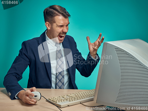 Image of Angry businessman using a monitor against blue background