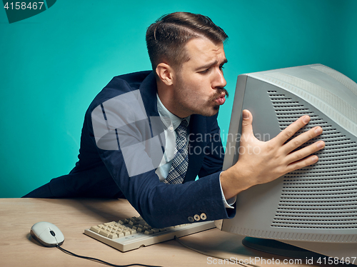 Image of Portrait of cheerful young businessman sitting with computer