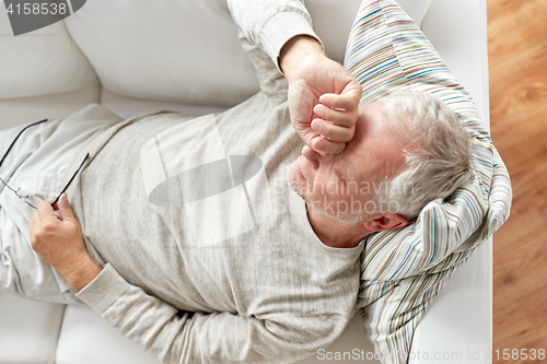 Image of close up of tired senior man lying on sofa at home