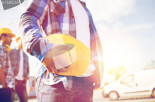 Image of close up of builder holding hardhat at building