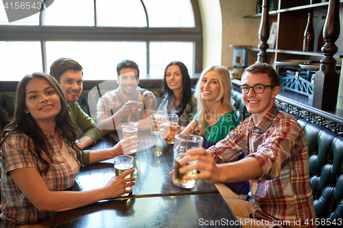 Image of happy friends drinking beer at bar or pub