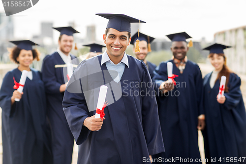 Image of happy students in mortar boards with diplomas