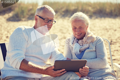 Image of happy senior couple with tablet pc on summer beach